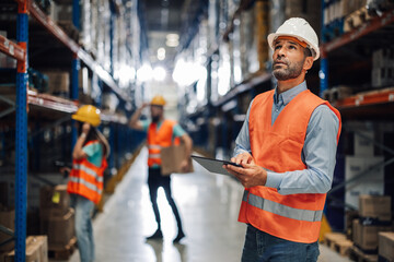 Warehouse supervisor evaluating inventory with tablet
