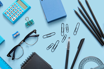 Different school stationery, notebooks and glasses on blue background