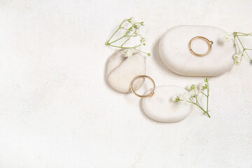 Stones with beautiful rings and gypsophila flowers on grunge white background