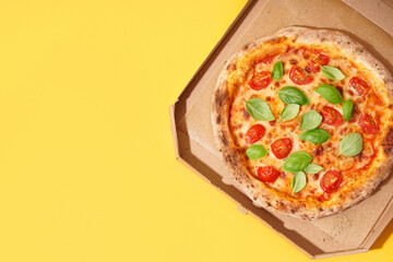 Carton box with tasty pizza Margarita on yellow background