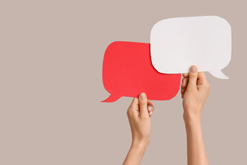 Female hands with speech bubbles on grey background