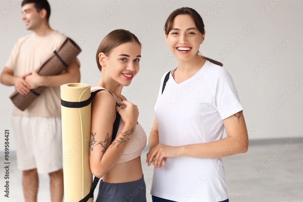 Wall mural sporty young women with yoga mats in gym