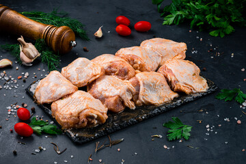 Portion marinated barbecue chicken with spices and salt on a dark background.