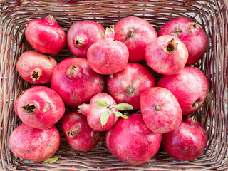 A group of red pomegranates in a wicker basket