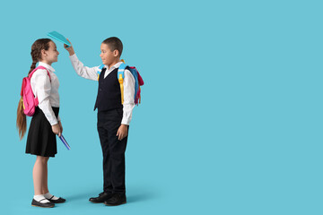 Fototapeta premium Happy little pupils with backpacks and notebooks having fun on blue background
