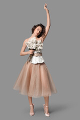 Naklejka premium Beautiful young woman with bouquet of blooming white lilac flowers on grey background