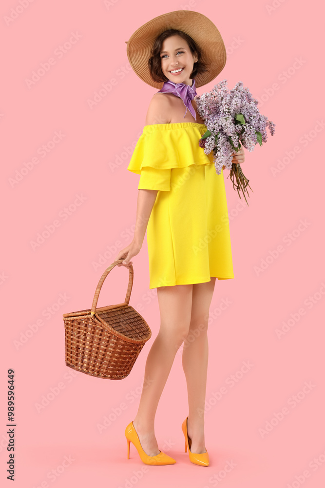 Poster beautiful young woman with bouquet of blooming lilac flowers and wicker basket on pink background