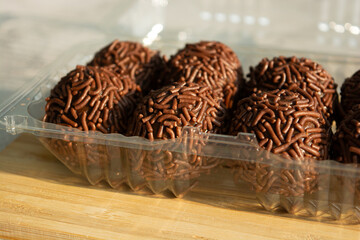 Close up of chocolate brigadeiros in a plastic container, ready to be enjoyed.