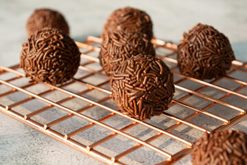 Closeup of chocolate brigadeiros on a cooling rack.