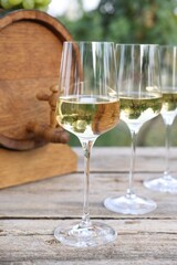 Tasty wine in glasses and barrel on wooden table outdoors