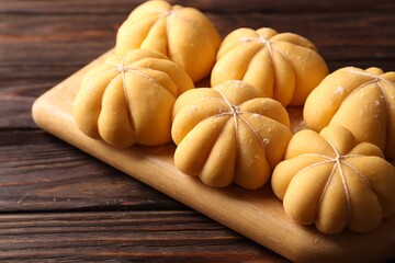 Raw pumpkin shaped buns on wooden table, closeup