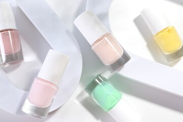 Nail polishes in bottles on white background, flat lay
