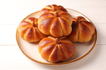 Tasty pumpkin shaped buns on white wooden table, closeup