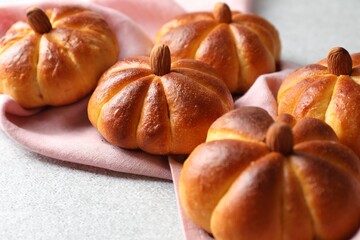 Tasty pumpkin shaped buns on light textured table, closeup