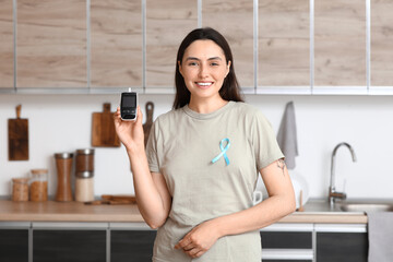 Diabetic young woman with blue awareness ribbon and glucometer in kitchen