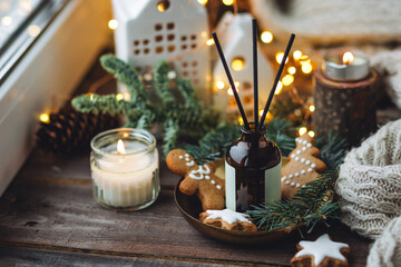 Christmas home aromatherapy. Aroma diffuser with pine extract, organic essential oil, cedar and spruce cone, cinnamon, anise, vanilla scent, candles, wooden table. Cozy atmosphere, winter inspiration