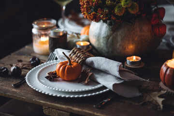 Elegant atmospheric beautiful dinner table setting for thanksgiving or wedding celebration, fall countryside style, pumpkins as decor. Romantic cozy home atmosphere. Wine, floral pumpkin centrepiece.