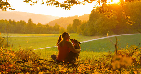 CLOSE UP: Woman enjoys a picturesque autumn evening in the countryside with her dog. Young woman...
