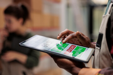 Small business manager supervising goods inventory using software application on tablet computer in storage room. Storehouse supervisor managing parcels transportation. Close up concept