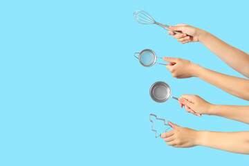 Female hands with different baking utensils on blue background