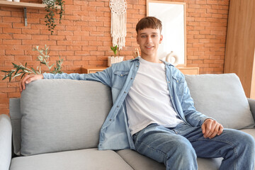 Young man sitting on grey sofa at home