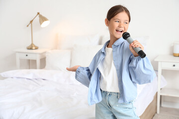 Little girl with microphone singing in bedroom