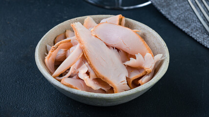 Chicken ham slices in a plate on a dark background.