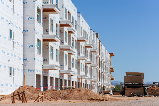 Exterior view of apartment buildings under construction, wrapped in high-density polyethylene material for air and water protection