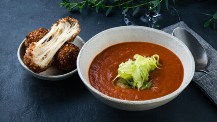 Tomato soup puree with fried cheese balls and herbs.