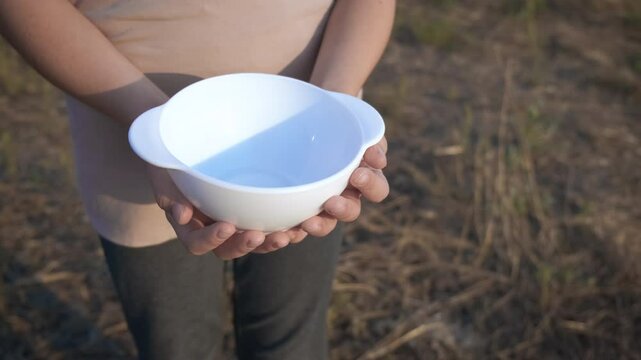 Child in migration with no food. A view of fugitive younger with empty plate begging for food in the urban place.