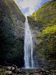 Fototapeta premium Scenic view of Hanakapiai Falls, a waterfall at the end of Hanakapiai Valley hiking trail, Kauai, Hawaii, USA against blue sky with clouds