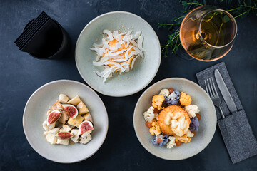 Set of breaded mozzarella cheese ball with cauliflower, cottage cheese casserole, different cheese and a glass of white wine.
