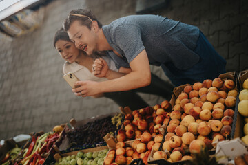 A happy duo explores a vibrant selection of fresh produce at a local marketplace, enjoying the experience of buying healthy fruits and vegetables.