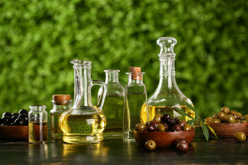 Decanters and bottles of fresh olive oil on black wooden table outdoors