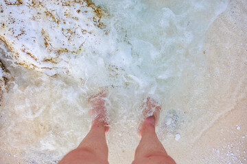 Fototapeta premium A person's feet are in the ocean water
