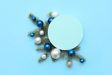 Composition with blank card, beautiful Christmas balls and fir branches on blue background