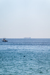 Calm blue sea with the silhouette of a large ship on the horizon