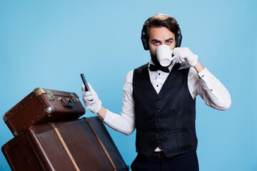 Innovative bellhop takes break drinking espresso and reading texts while enjoying soundtracks on...