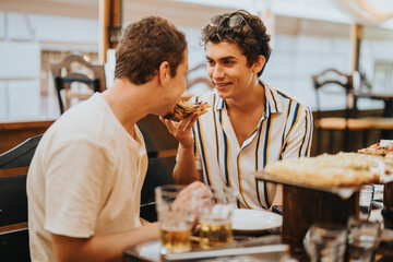 Two friends share a light moment over pizza and drinks in a relaxed restaurant setting. The atmosphere is casual and joyful, emphasizing friendship and leisure time.