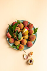 Lychee with green leaf on the plate, top view. Tropical fruits background