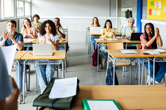Group of diverse high school students applauding to their classmate after giving a presentation in classroom. Education concept. - Powered by Adobe