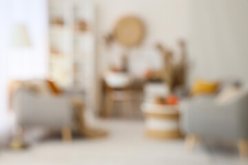 Blurred view of light living room with autumn decor, sofa and armchairs