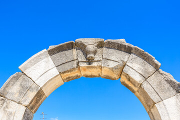 A stone archway with a stone carving of a bear on it. Ruins of the ancient city of Philippi, Greece