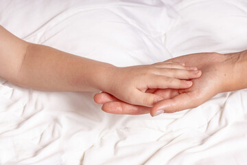 Baby's hands in woman's hands on white background.