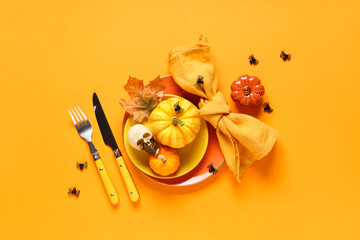 Beautiful table setting with fresh pumpkins, skull and spiders for Halloween celebration on orange...