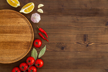 Wooden cutting board and vegetables with spices, top view. Cooking layout