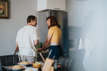 A couple enjoys time together in a cozy kitchen, preparing a meal and sharing smiles. The modern kitchen environment adds to the warm and relaxed atmosphere.