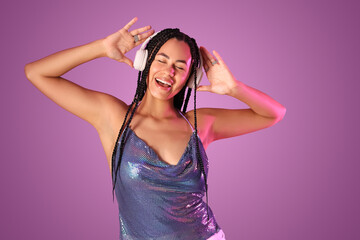 Beautiful young African-American woman with braids in headphones on purple background