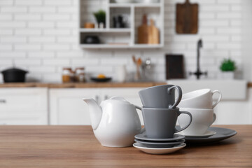 Porcelain teapot, cups and saucers on wooden counter in kitchen