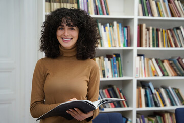 Cute young caucasian dark-haired woman in the library looking busy and involved